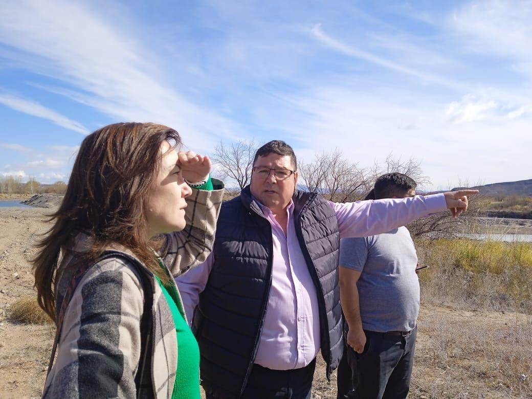 Recorrida a la vera de un río: tres personas observan el terreno mientras una señala el horizonte.